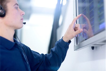 engineer at industry control room - Low angle side view of young man wearing headset using touch screen computer monitor Stock Photo - Premium Royalty-Free, Code: 649-08328778