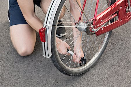 Cropped view of young man kneeling inflating bicycle tyre Photographie de stock - Premium Libres de Droits, Code: 649-08328847