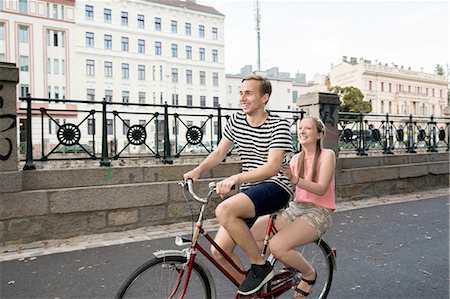 simsearch:649-08307271,k - Young man riding bicycle with young woman sitting on back smiling Stock Photo - Premium Royalty-Free, Code: 649-08328848