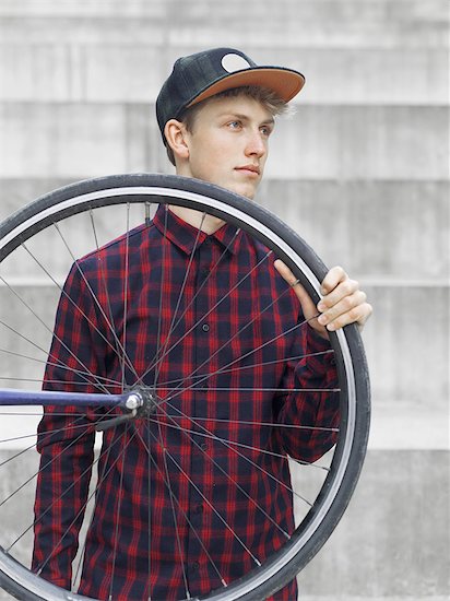 Urban cyclist carrying tyre in front of steps Foto de stock - Sin royalties Premium, Código de la imagen: 649-08381017