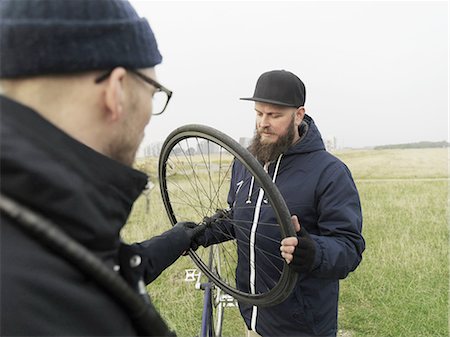 Urban cyclists fixing tyre in field Stock Photo - Premium Royalty-Free, Code: 649-08381026