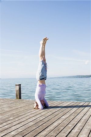 simsearch:649-08423361,k - Mature woman on pier by ocean balancing on head Stock Photo - Premium Royalty-Free, Code: 649-08381061