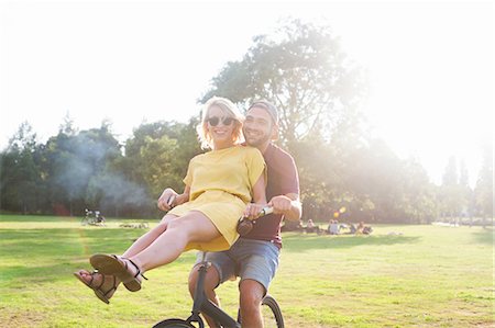 simsearch:649-08577651,k - Portrait of young couple having fun on bicycle at sunset party in park Stock Photo - Premium Royalty-Free, Code: 649-08381104