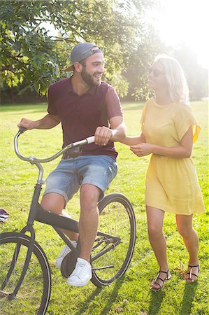 sunglasses wearing men - Young couple cycling in sunlit park Stock Photo - Premium Royalty-Free, Code: 649-08381100