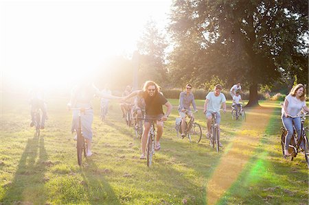 Crowds of adult friends arriving on bicycles to sunset park party Stock Photo - Premium Royalty-Free, Code: 649-08381114