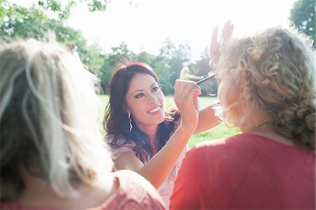 simsearch:649-08179955,k - Female adult friends applying make up at sunset park party Fotografie stock - Premium Royalty-Free, Codice: 649-08381118