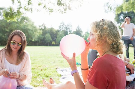 Young woman blowing up balloon at park party Stock Photo - Premium Royalty-Free, Code: 649-08381129