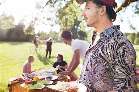 Young man with plate of picnic food at park party Stock Photo - Premium Royalty-Free, Code: 649-08381144