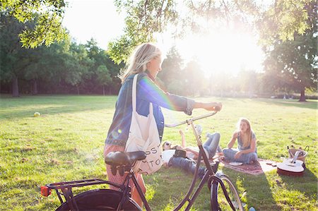 Young woman arriving on bicycle to sunset park party Stock Photo - Premium Royalty-Free, Code: 649-08381167