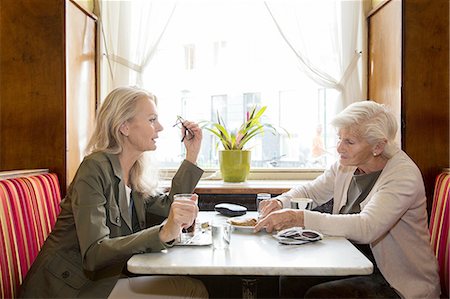 simsearch:649-08381348,k - Mother and daughter sitting together in cafe Fotografie stock - Premium Royalty-Free, Codice: 649-08381339