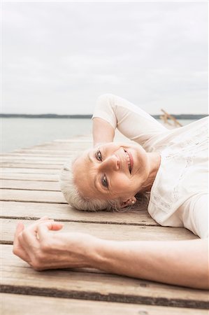 simsearch:649-08381569,k - Senior woman relaxing on pier, smiling, elevated view Stock Photo - Premium Royalty-Free, Code: 649-08381562