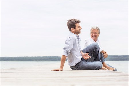 simsearch:649-08381555,k - Two men sitting on pier, relaxing, smiling Photographie de stock - Premium Libres de Droits, Code: 649-08381572