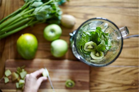 entgiften - Woman cutting green kiwi on wooden table Foto de stock - Sin royalties Premium, Código: 649-08422492