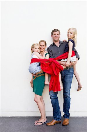 simsearch:649-08060405,k - Portrait of parents and two daughters wrapped in red ribbon in front of white wall Stock Photo - Premium Royalty-Free, Code: 649-08422513