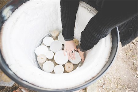 High angle view of young woman arms reaching into barrel kiln for clay pot Photographie de stock - Premium Libres de Droits, Code: 649-08422683