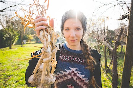 Young woman in garden holding freshly picked garlic bulbs looking at camera smiling Stock Photo - Premium Royalty-Free, Code: 649-08422697
