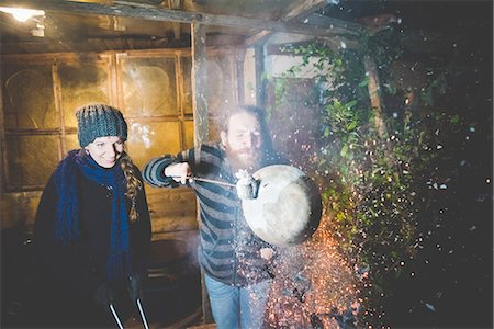 Couple holding hot clay pot in tongs, blowing, causing sparks Photographie de stock - Premium Libres de Droits, Code: 649-08422735