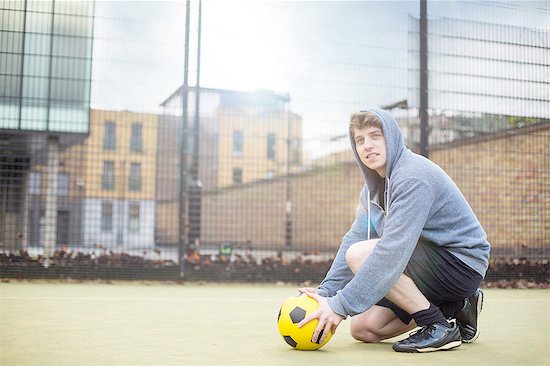 Young man setting football on floor, on urban football pitch Foto de stock - Sin royalties Premium, Código de la imagen: 649-08422774