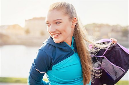 simsearch:649-08422865,k - Mid adult female runner putting on tracksuit top at city riverside Stock Photo - Premium Royalty-Free, Code: 649-08422849
