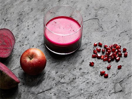 High angle view of purple raw juice, halved beetroot, apple and pomegranate seeds Photographie de stock - Premium Libres de Droits, Code: 649-08422902