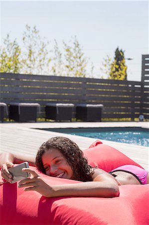 Girl lying on poolside cushion reading smartphone, Cassis, Provence, France Photographie de stock - Premium Libres de Droits, Code: 649-08422956