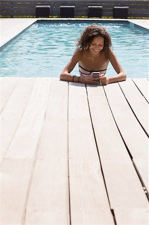 Girl in swimming pool reading smartphone texts, Cassis, Provence, France Foto de stock - Royalty Free Premium, Número: 649-08422959