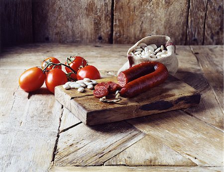 Roma tomatoes on the vine, chorizo and butter beans in burlap sack on wooden cutting board Stock Photo - Premium Royalty-Free, Code: 649-08423051