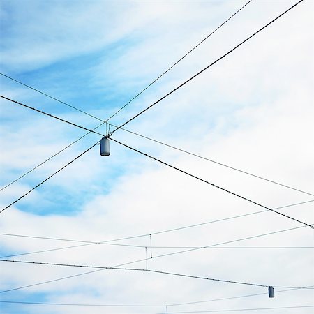 Low angle view of blue sky and street lights with criss crossed wires Stock Photo - Premium Royalty-Free, Code: 649-08423207