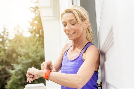 Mature female runner checking smartwatch at front door Photographie de stock - Premium Libres de Droits, Code: 649-08423221