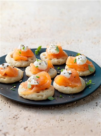 Smoked salmon and cream cheese on blinis with chive and black pepper garnish Photographie de stock - Premium Libres de Droits, Code: 649-08423292