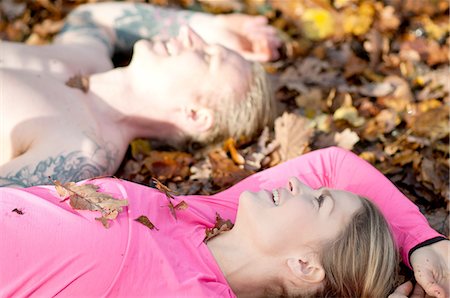 simsearch:649-08969027,k - Side view of couples head and shoulders lying on autumn leaves looking up smiling Foto de stock - Sin royalties Premium, Código: 649-08423330