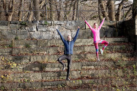 simsearch:649-08423361,k - Full length front view of couple on stone steps, arms raised standing on one leg Stock Photo - Premium Royalty-Free, Code: 649-08423359