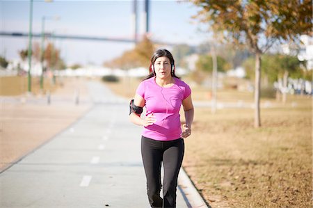 simsearch:614-08641269,k - Front view of mature woman wearing headphones and armband jogging on pathway Stock Photo - Premium Royalty-Free, Code: 649-08423408