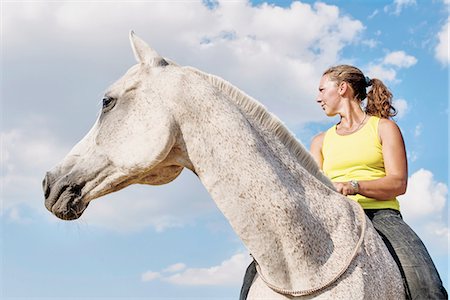 Low angle view of woman riding grey horse bareback against blue sky Stock Photo - Premium Royalty-Free, Code: 649-08423428