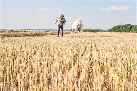 Man training galloping white horse in field Stock Photo - Premium Royalty-Free, Code: 649-08423434