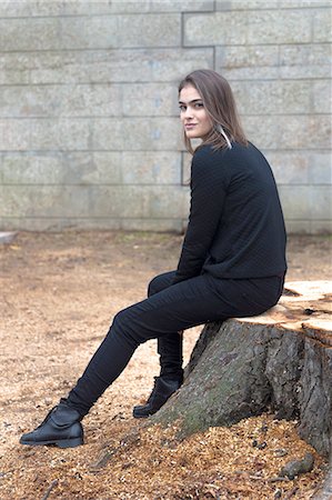 Young woman sitting on tree stump Stock Photo - Premium Royalty-Free, Code: 649-08479328