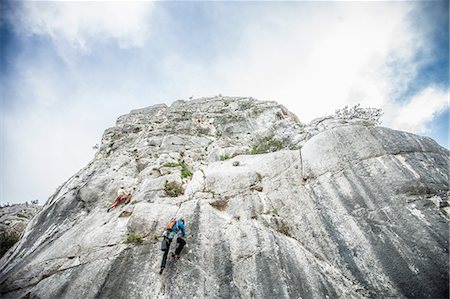 Low angle rear view of rock climber climbing up mountainside, Ogliastra, Sardinia, Italy Stock Photo - Premium Royalty-Free, Code: 649-08479377
