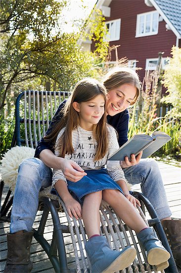 Mother and daughter sitting on chair outdoors reading book Foto de stock - Sin royalties Premium, Código de la imagen: 649-08479518