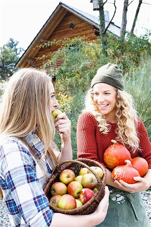 Two friends carrying homegrown produce, one woman eating apple Photographie de stock - Premium Libres de Droits, Code: 649-08479511