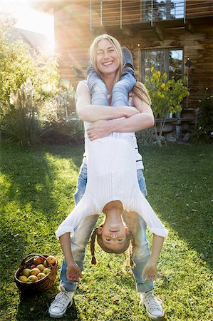 family portrait building - Mother lifting daughter upside down in garden Stock Photo - Premium Royalty-Free, Code: 649-08479533