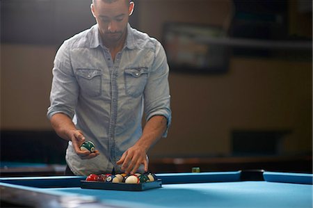 Man arranging balls into triangle on pool table Fotografie stock - Premium Royalty-Free, Codice: 649-08480191