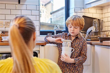 Boy carrying stack of mugs in kitchen Photographie de stock - Premium Libres de Droits, Code: 649-08544046