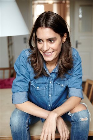 sitting in jeans - Portrait of beautiful young woman sitting on dining table Stock Photo - Premium Royalty-Free, Code: 649-08544067