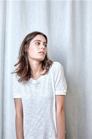 soupçon (suspicion) - Portrait of young woman standing in front of curtain Photographie de stock - Premium Libres de Droits, Code: 649-08544062