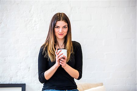 simsearch:649-08544187,k - Portrait of beautiful young woman in apartment holding coffee mug Foto de stock - Sin royalties Premium, Código: 649-08544177