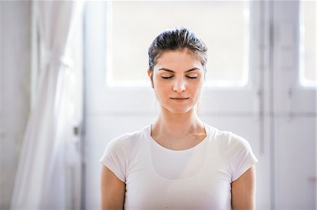 Young woman meditating with eyes closed in apartment Stock Photo - Premium Royalty-Free, Code: 649-08544195