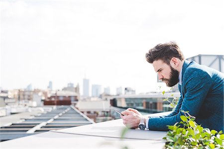 simsearch:649-08577542,k - Young businessman reading smartphone text on office roof terrace Stock Photo - Premium Royalty-Free, Code: 649-08544257