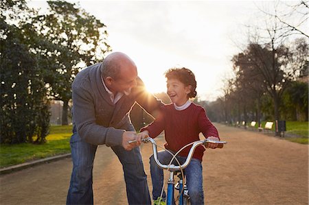 Grandfather teaching grandson to ride bicycle in park Photographie de stock - Premium Libres de Droits, Code: 649-08544309