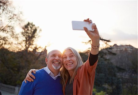family outdoor lens flare - Couple using smartphone to take selfie smiling Stock Photo - Premium Royalty-Free, Code: 649-08544344