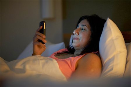 simsearch:614-08544994,k - Mature woman reading smartphone texts in hotel bed at night Foto de stock - Sin royalties Premium, Código: 649-08548062